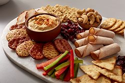 Platter of crackers, dip, veggies, and meat